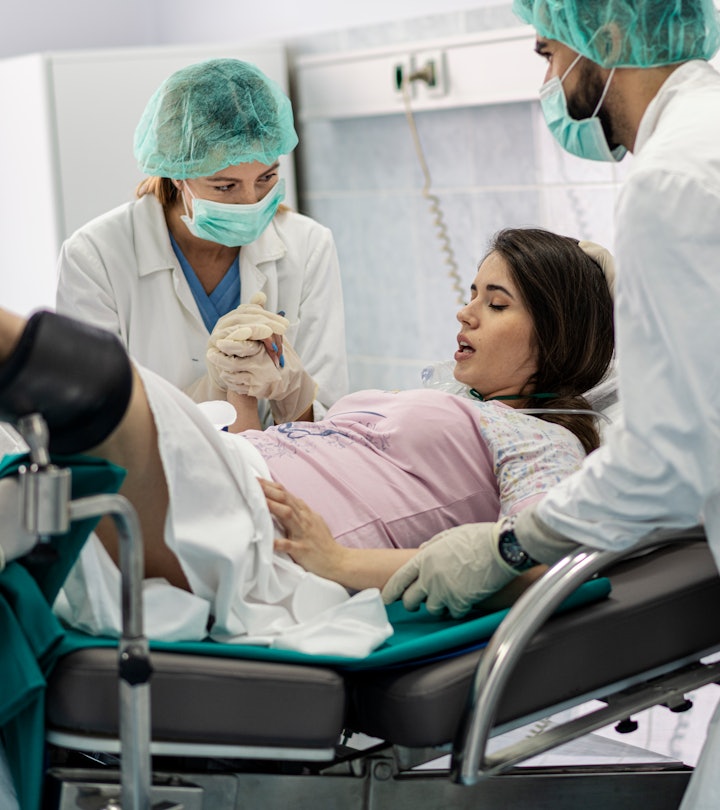 Obstetricians assisting in the hospital woman in labor pushes to give birth
