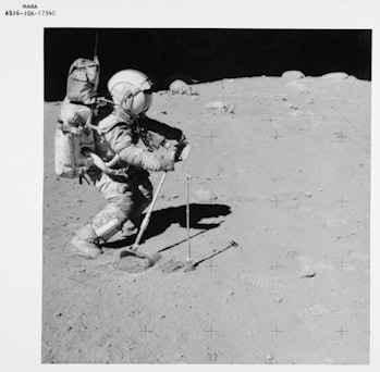 American NASA astronaut John W Young using the lunar surface rake and a set of tongs to collect luna...