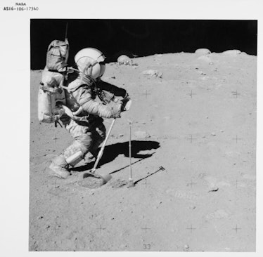 American NASA astronaut John W Young using the lunar surface rake and a set of tongs to collect luna...