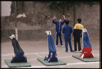 Chinese citizens perform morning stretching exercises on mats.   (Photo by Peter Turnley/Corbis/VCG ...