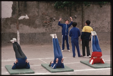 Chinese citizens perform morning stretching exercises on mats.   (Photo by Peter Turnley/Corbis/VCG ...