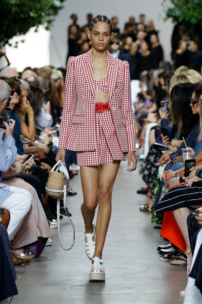A model at the Michael Kors show at New York Fashion Week in 2019 wears a Gingham blazer, bra and sk...