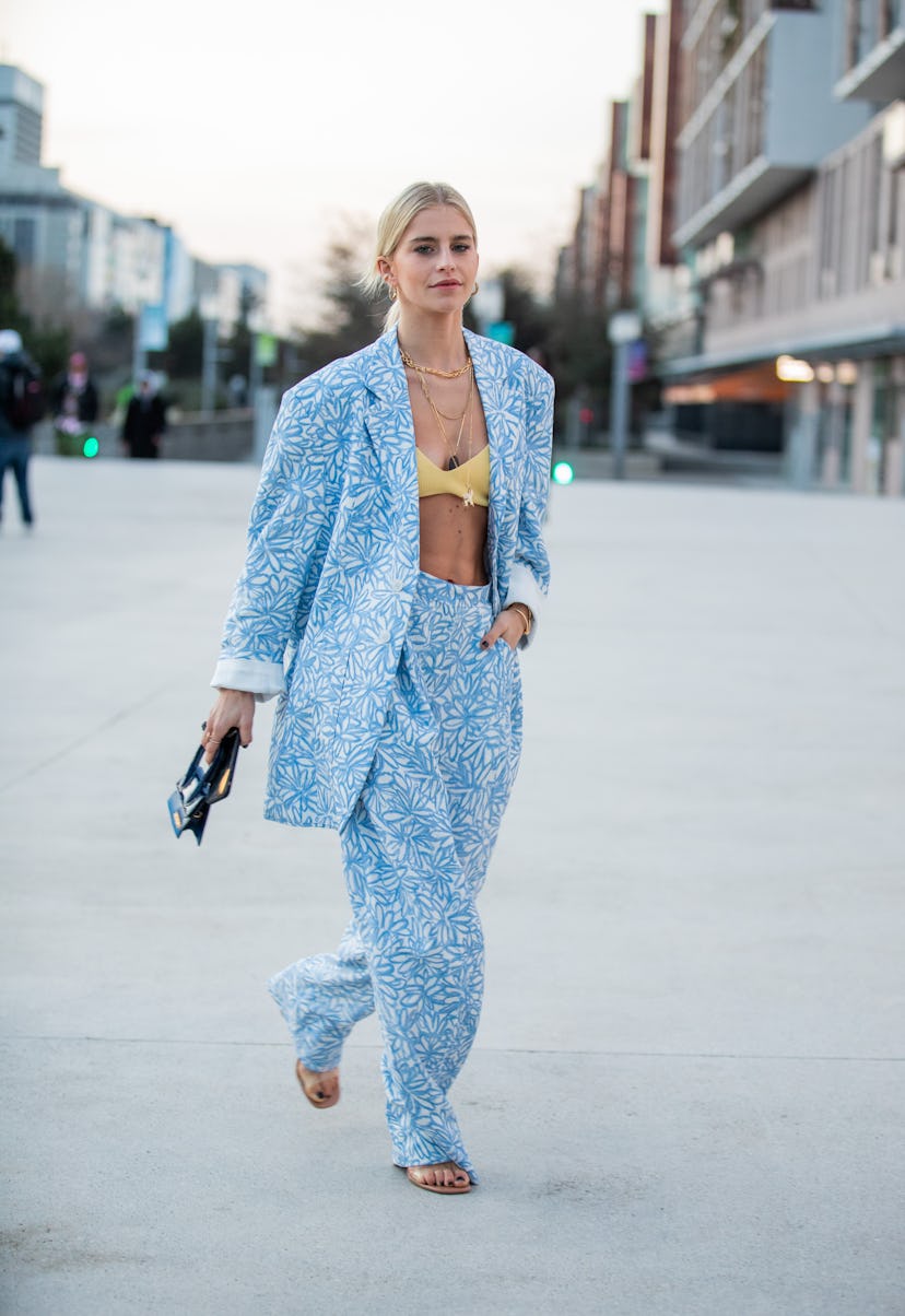 Caro Daur in a graphic blue suit with a yellow bra underneath is at Paris Fashion Week in 2020. 