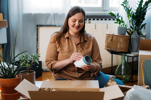 A woman wraps ceramics in a moving box. Here's your daily horoscope for February 11, 2022.
