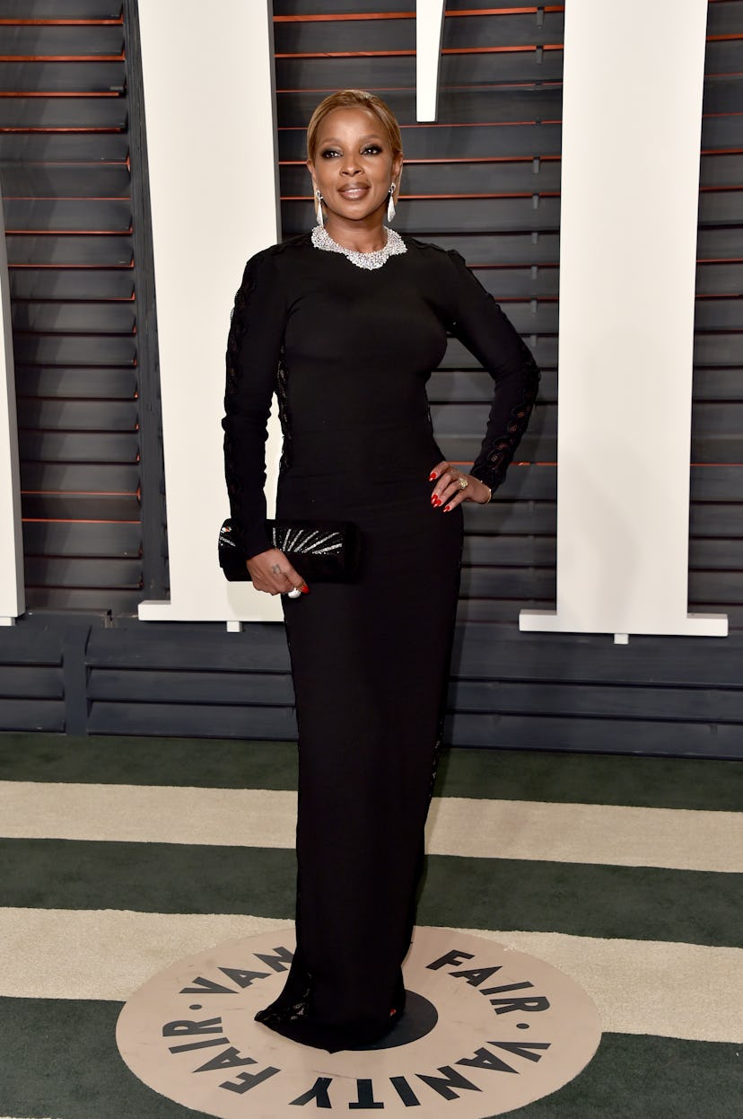 Mary J. Blige at an Oscars party in a long-sleeve, black gown with crystal embellishments.