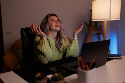 Tired young woman working in home office at night