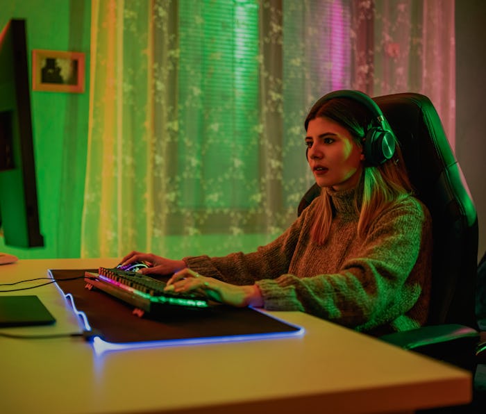 Excited young female Gamer in Headset Playing Online Video Game on Computer at home.