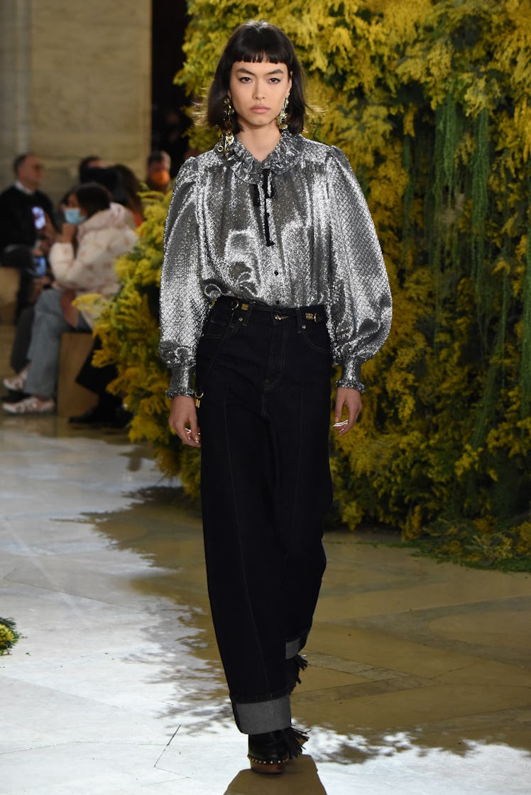 Model on the NY Fashion Week Fall 2022 runway in Ulla Johnson silver ruffle shirt and dark denim pan...
