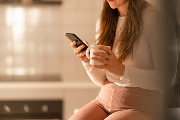 Woman is at home by herself in her apartment in the city. She is browsing through social media on he...