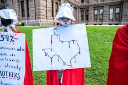 AUSTIN, TX - MAY 29: A protester dressed as a handmaiden holds up a sign at a protest outside the Te...