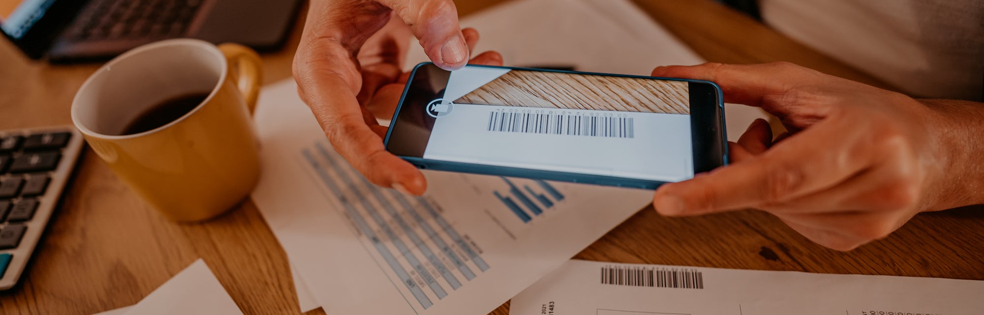 Handsome man paying bills via bar code payments. He is scanning bar code on the bill with his phone.