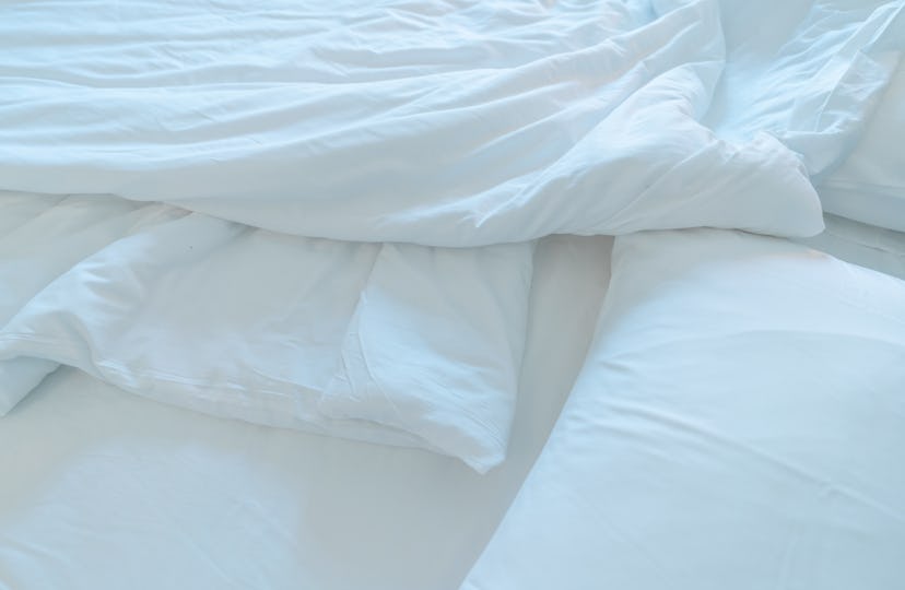 White comfort bed and soft pillow in modern bedroom. White linen blanket in hotel bedroom. Closeup d...