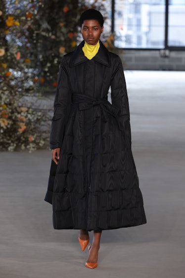 Model on the NY Fashion Week Fall 2022 in Jason Wu yellow turtleneck and black puffy coat with brown...