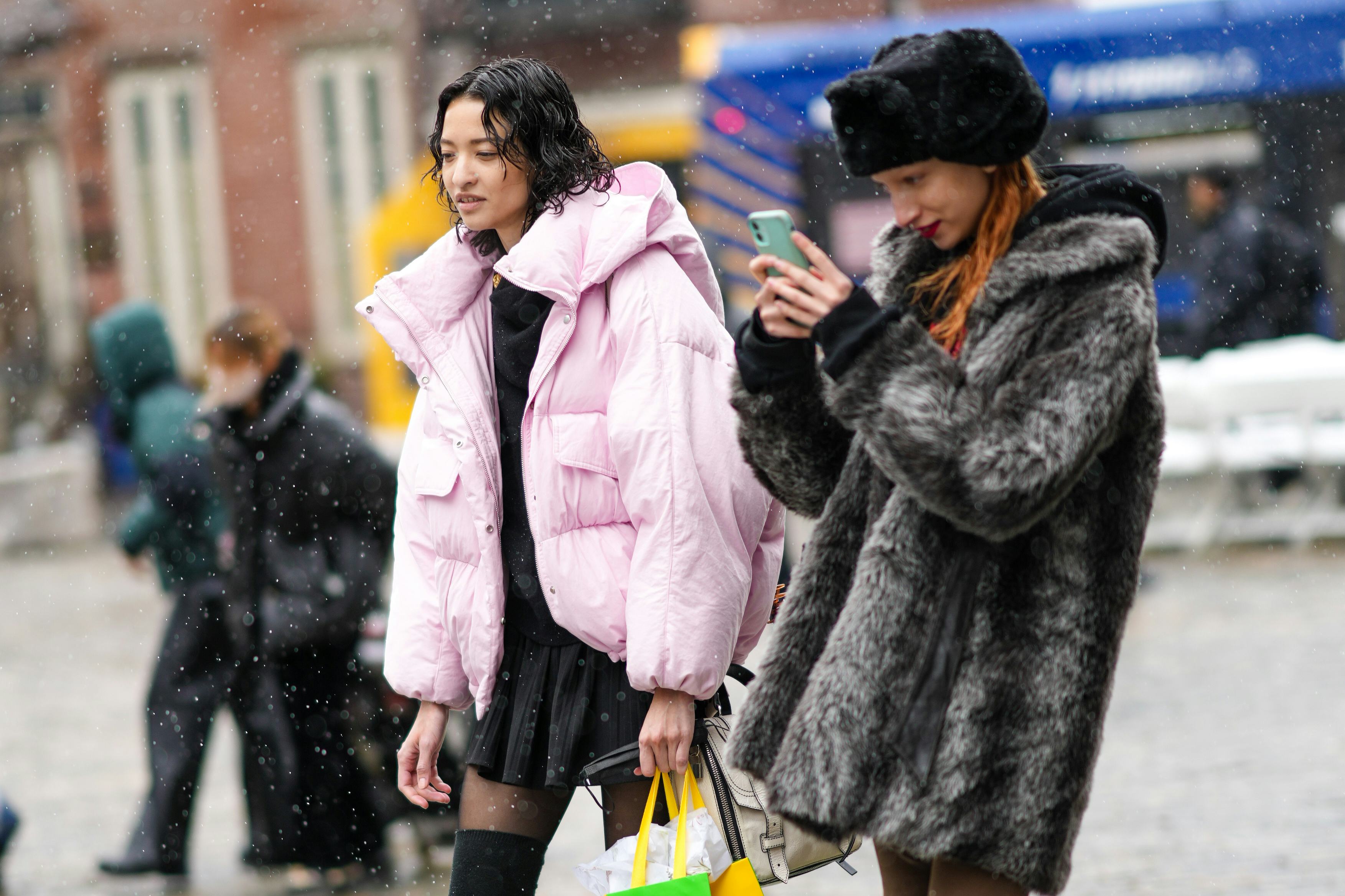 NEW YORK, NEW YORK - FEBRUARY 13: A model (L) wears a black high neck pullover, a black short pleate...