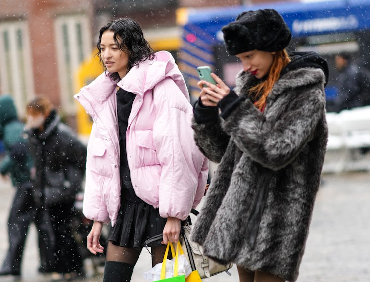 NEW YORK, NEW YORK - FEBRUARY 13: A model (L) wears a black high neck pullover, a black short pleate...