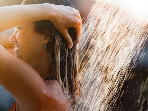 Young happy woman enjoying while taking a shower in nature.