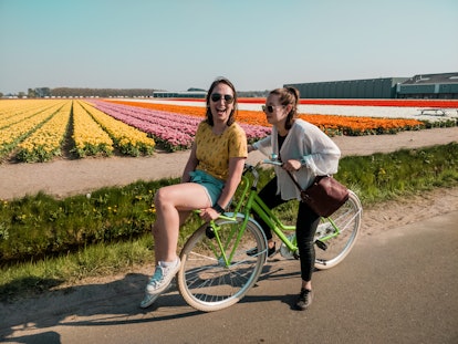 young women ride a bike together as they discuss spring equinox 2022, and what signs will be affecte...