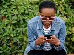 A woman laughing at funny adult memes on her phone. 