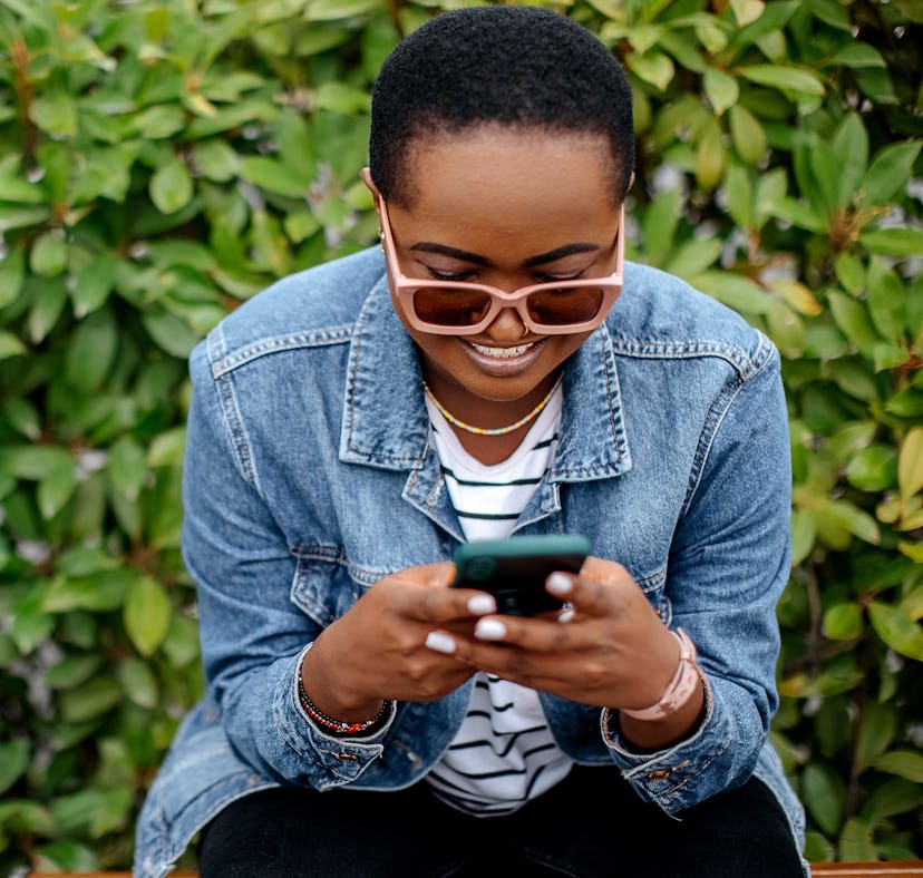 A woman laughing at funny adult memes on her phone.