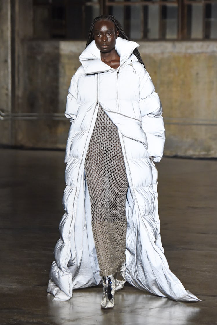 Model on the NY Fashion Week Fall 2022 runway in a Dion Lee see-through dress and a long puffer jack...