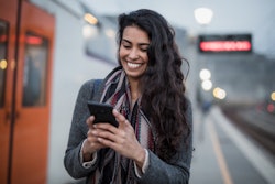 Smiling woman using smart phone on station. Here's how to read DMs on instagram without being seen b...