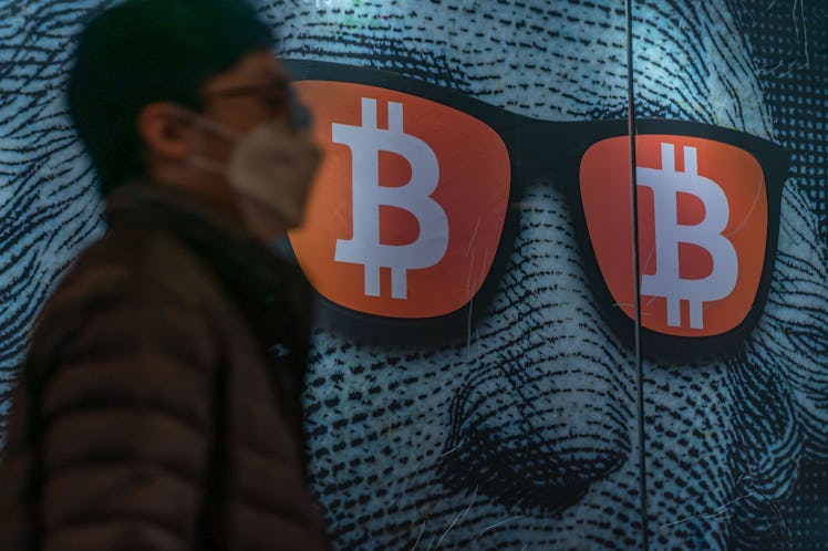 HONG KONG, CHINA - FEBRUARY 15: Pedestrians walk past a display of cryptocurrency Bitcoin on Februar...