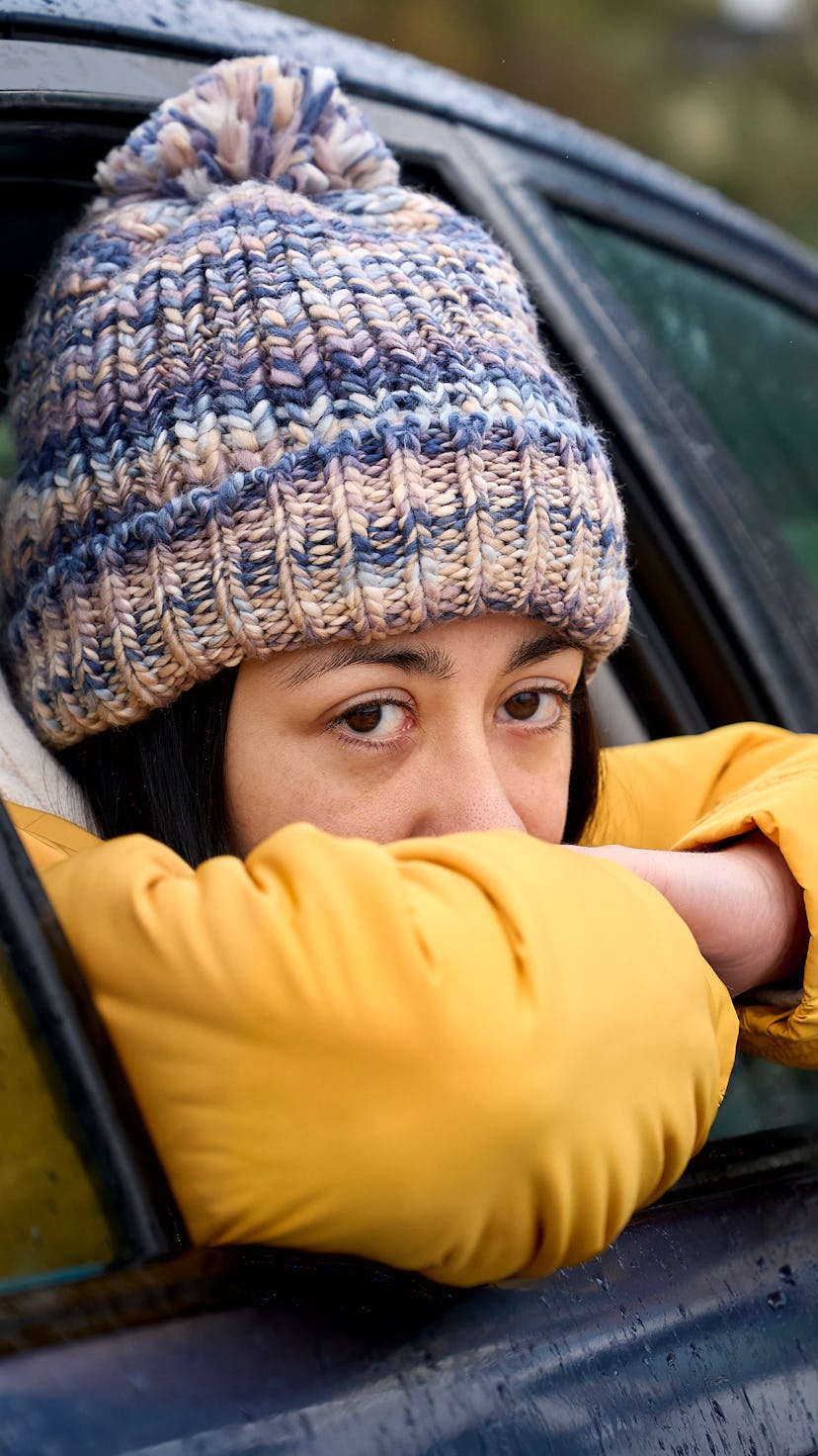 Young girl wearing a yellow navy coat and hat looks out of a car window. Pisces season begins on Feb...