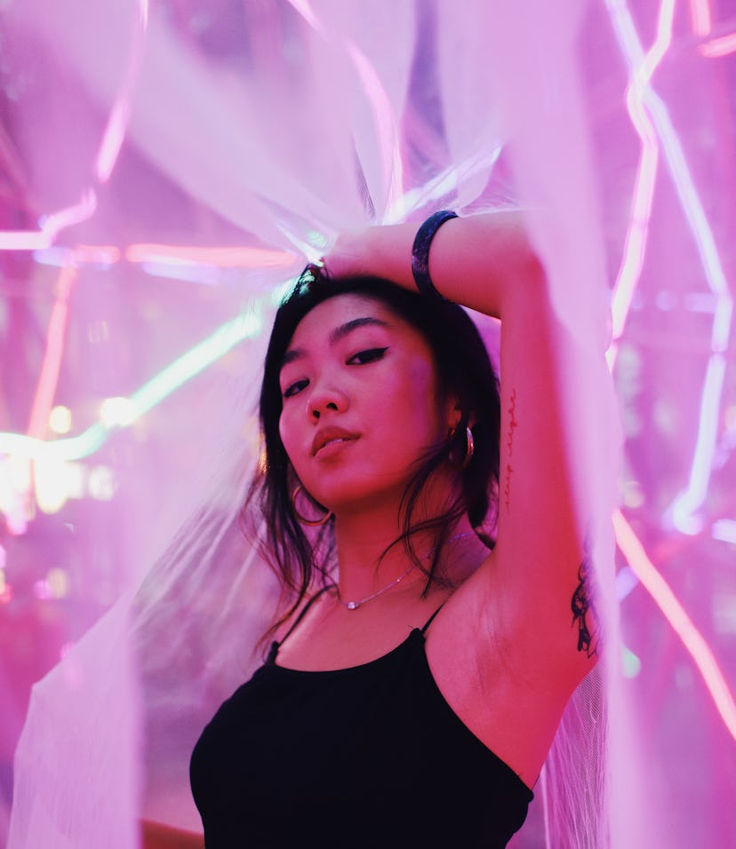 Young woman standing in pink neon light, knowing her unlucky zodiac sign will have the worst month o...