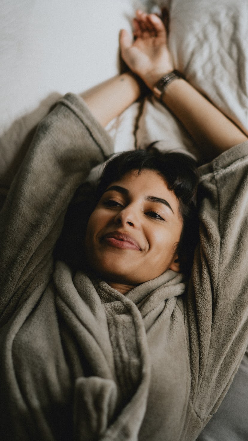 Young woman resting lying in bed. Use Pisces season 2022 to dream big and keep a dream journal.