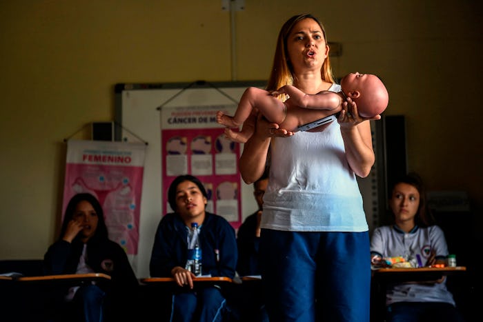 A sex education teacher shows students how to hold a baby, using a baby robot, at a school in Caldas...