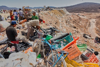 'Recyclers' collecting recyclables of cardboard, plastics and tin on a garbage dump mountain in the ...
