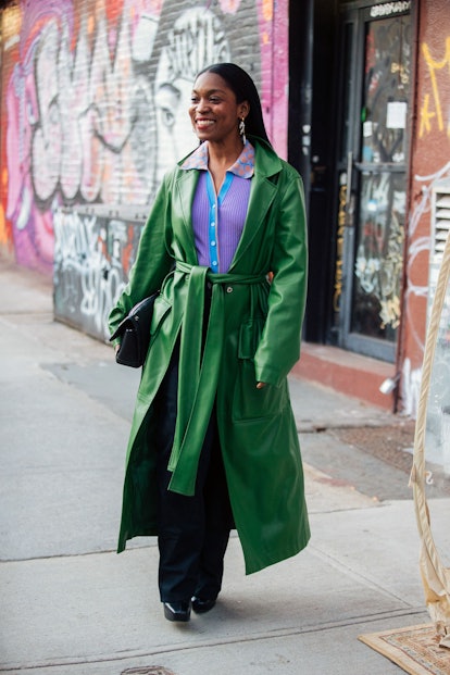 NEW YORK, NEW YORK - FEBRUARY 11: Rajni Jacques wears a green leather belted trench coat, purple but...