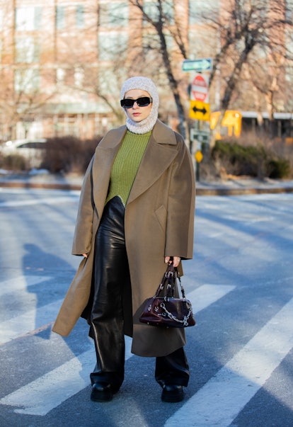 NEW YORK, NEW YORK - FEBRUARY 15: A guest is seen wearing knitted balaklava, olive green coat, Loewe...