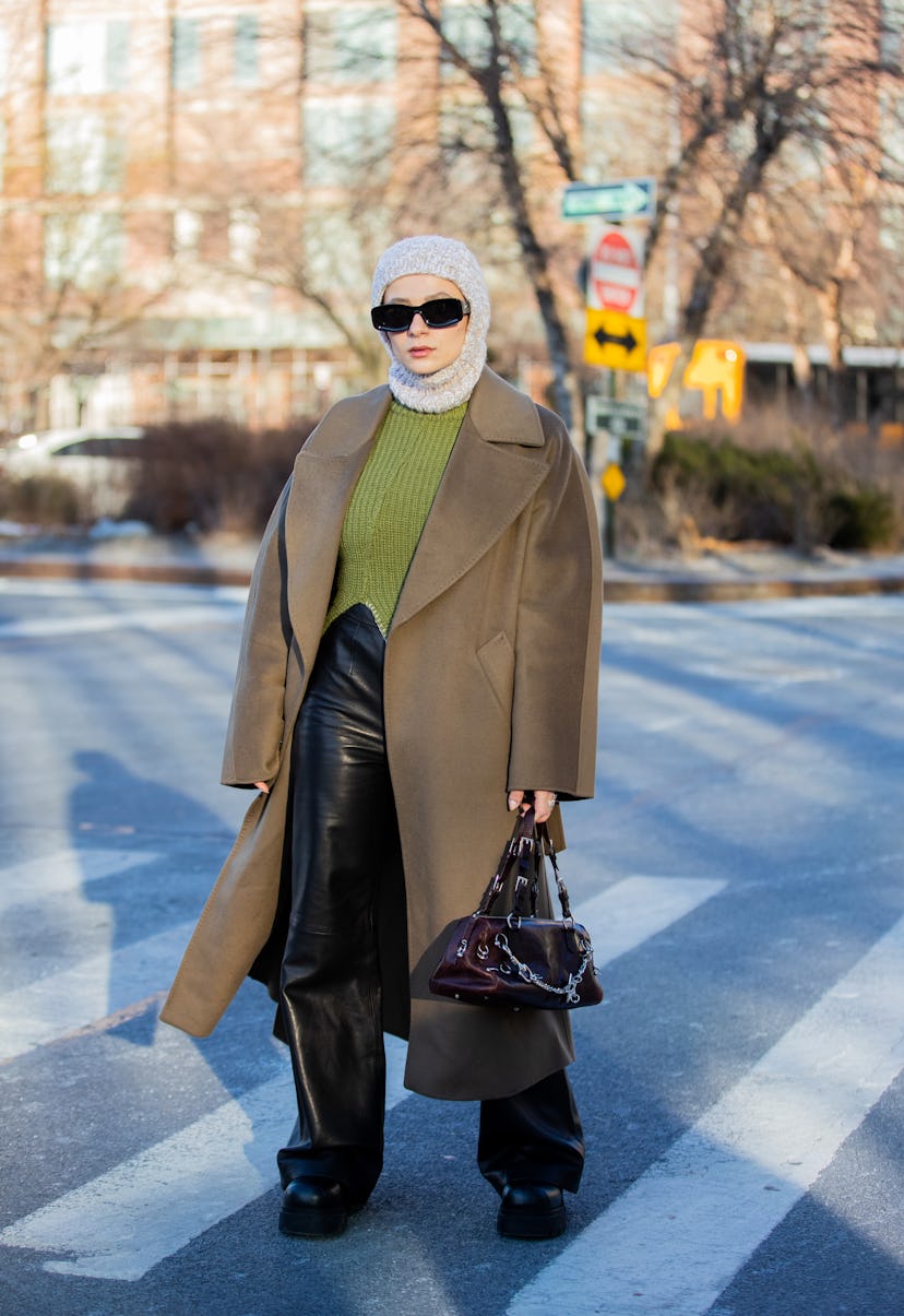 NEW YORK, NEW YORK - FEBRUARY 15: A guest is seen wearing knitted balaklava, olive green coat, Loewe...