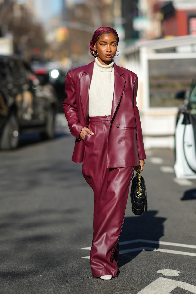 NEW YORK, NEW YORK - FEBRUARY 11: A guest wears a burgundy silk scarf as a hat, gold earrings, a whi...