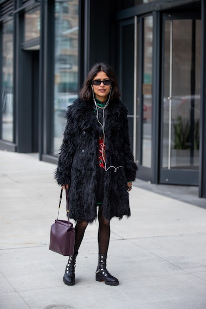 NEW YORK, NEW YORK - FEBRUARY 16: A guest is seen wearing black faux fur coat, bordeaux colored bag,...