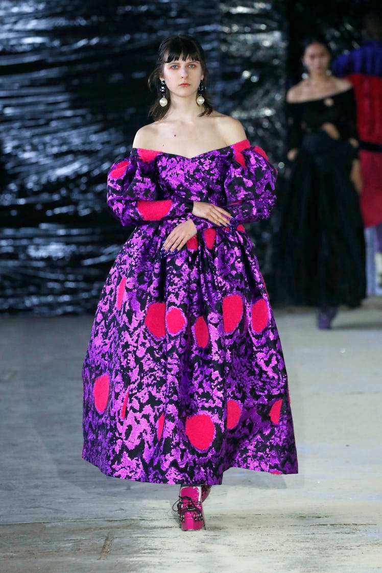 A model in a purple-black-pink metallic dress with puff sleeves by Edward Crutchley