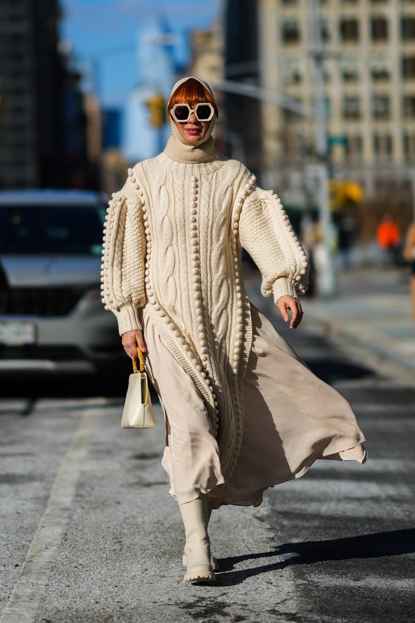 NEW YORK, NEW YORK - FEBRUARY 14: A guest wears a beige wool balaclava, a beige wool embroidered pom...