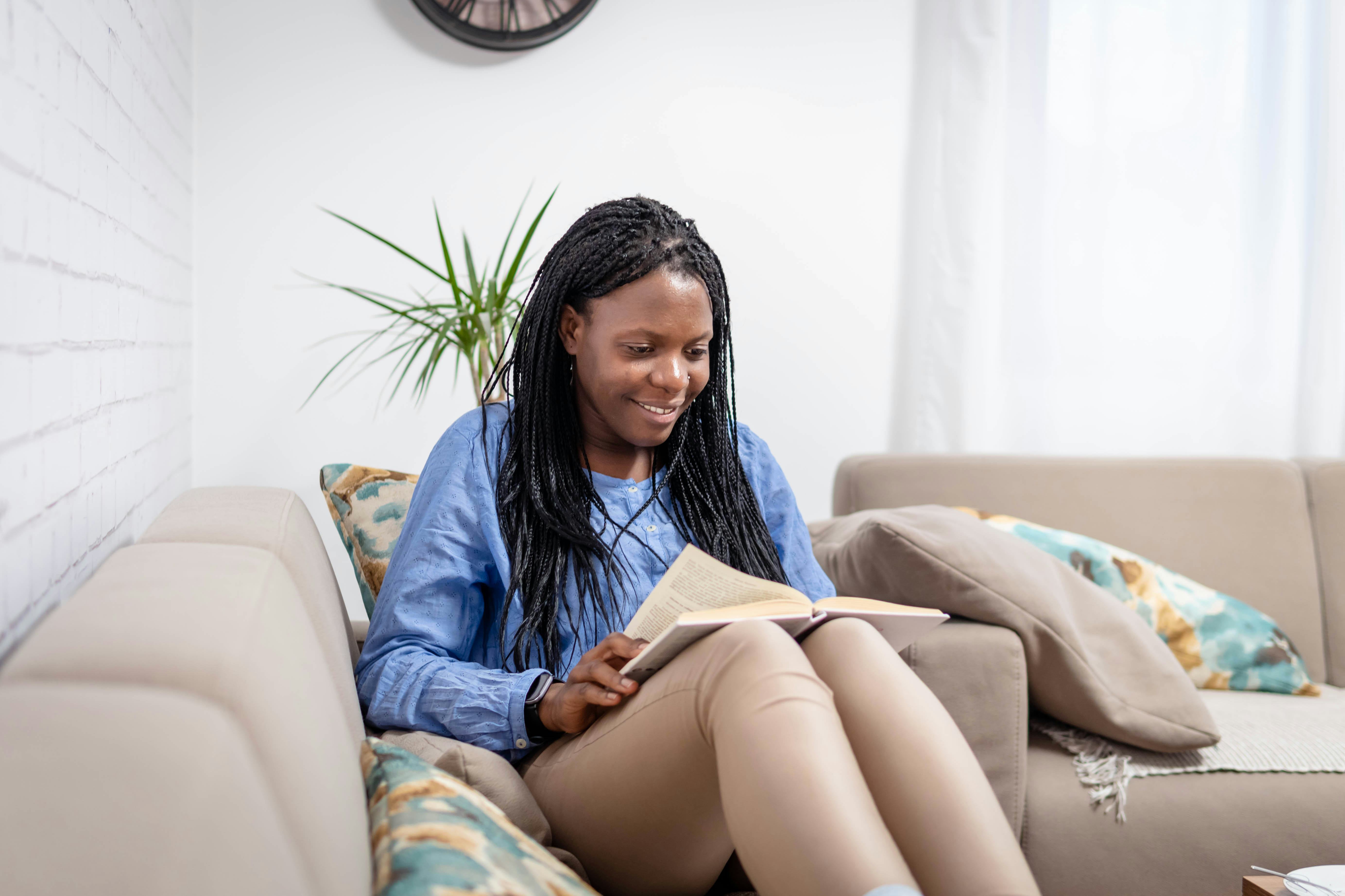 Beautiful african american smiling woman reading a book at home.