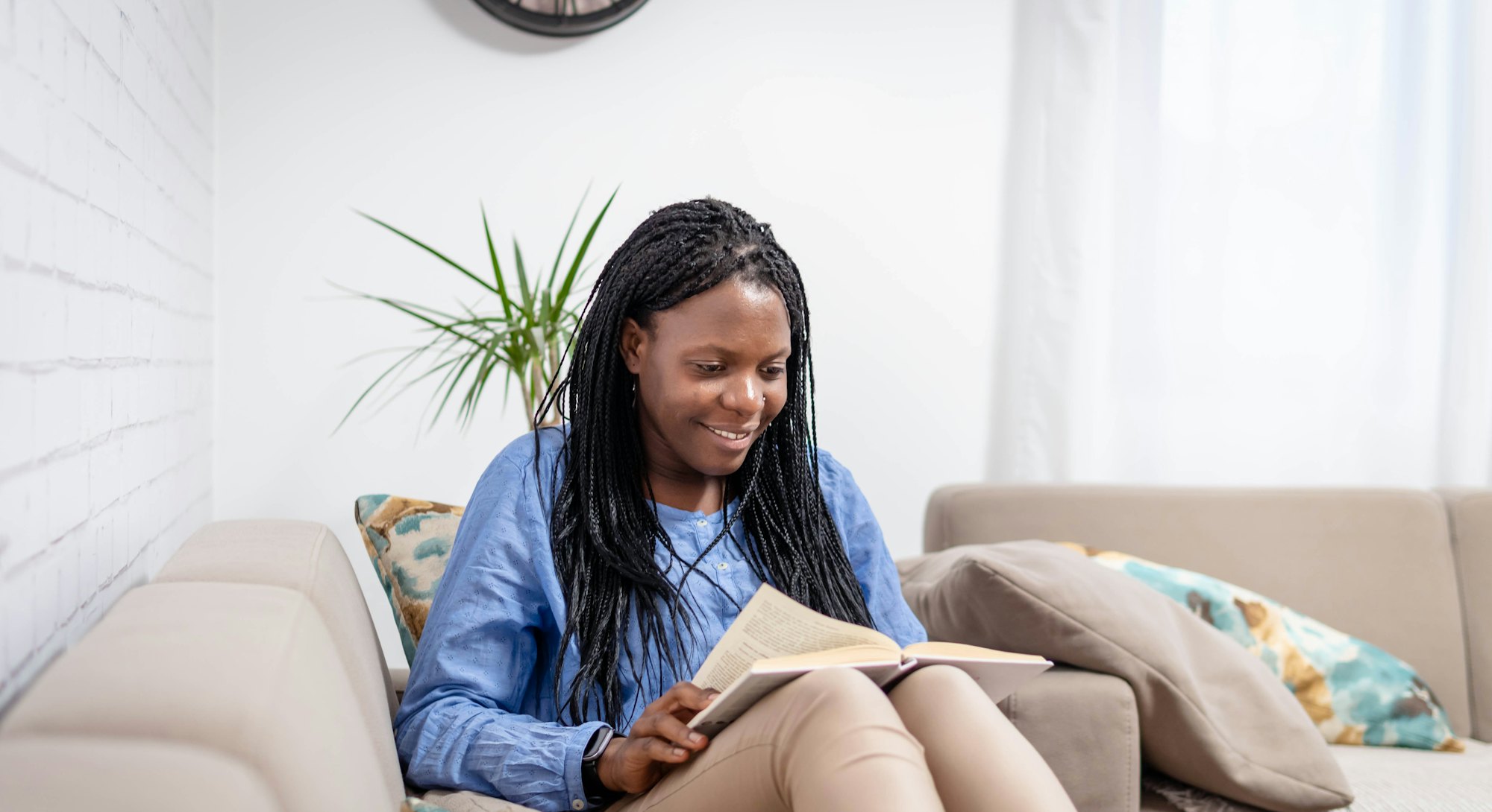 Beautiful african american smiling woman reading a book at home.