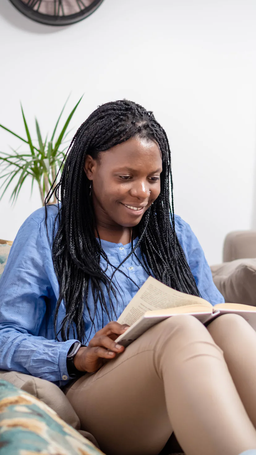 Beautiful african american smiling woman reading a book at home.