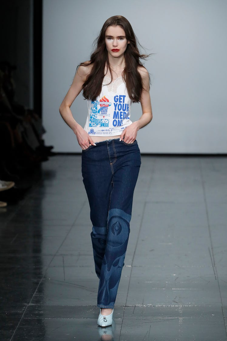 A model in a white shirt with print and blue denim jeans by Conner Ives