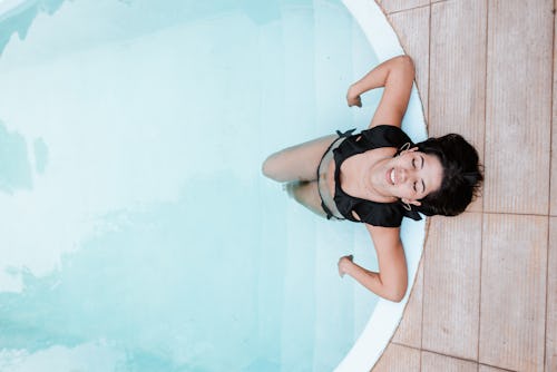 A woman leans back out of a pool. Here's your guide to pisces season dates, meaning, and more astrol...