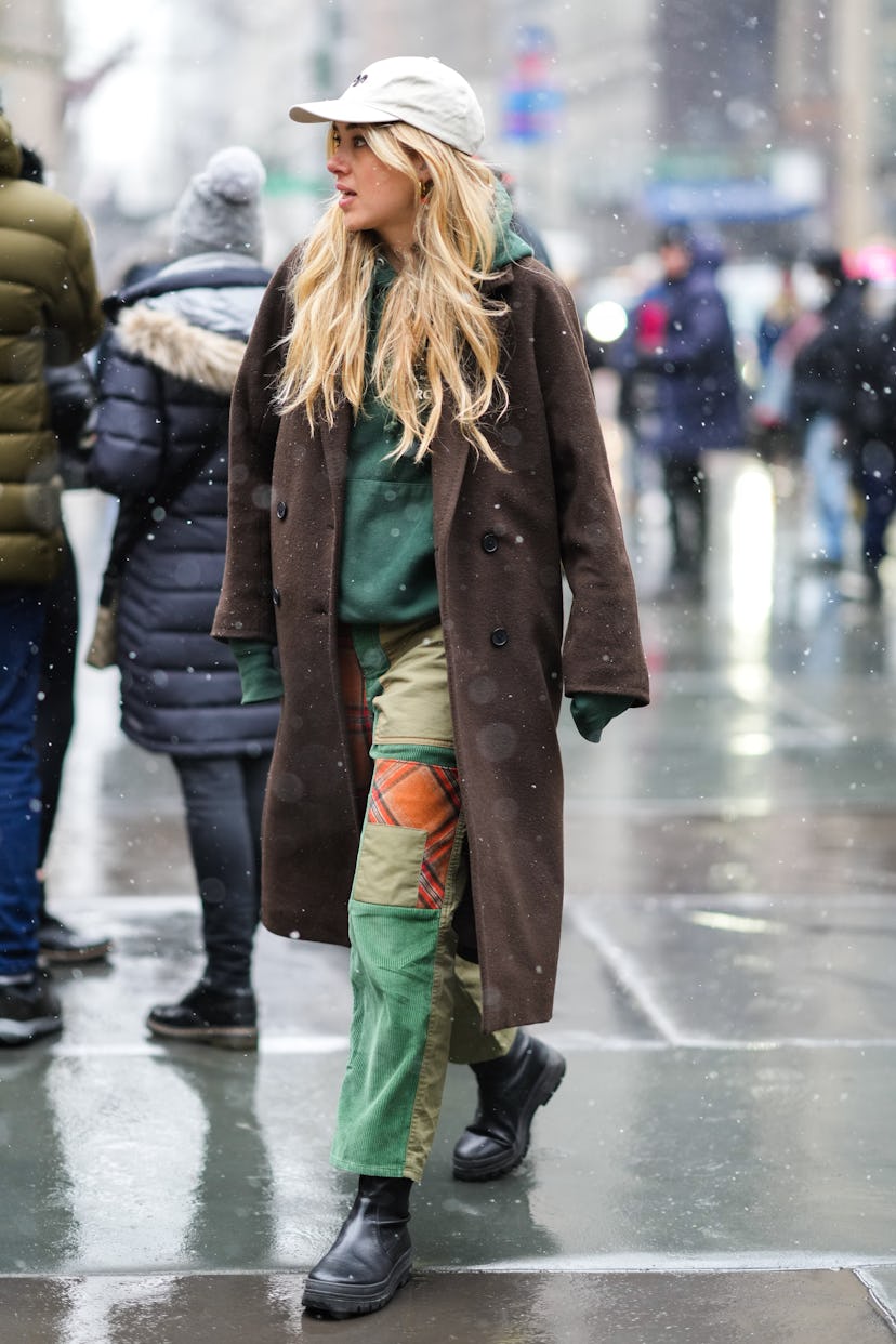 NEW YORK, NEW YORK - FEBRUARY 13: A guest wears a white latte cap with black embroidered pattern, a ...