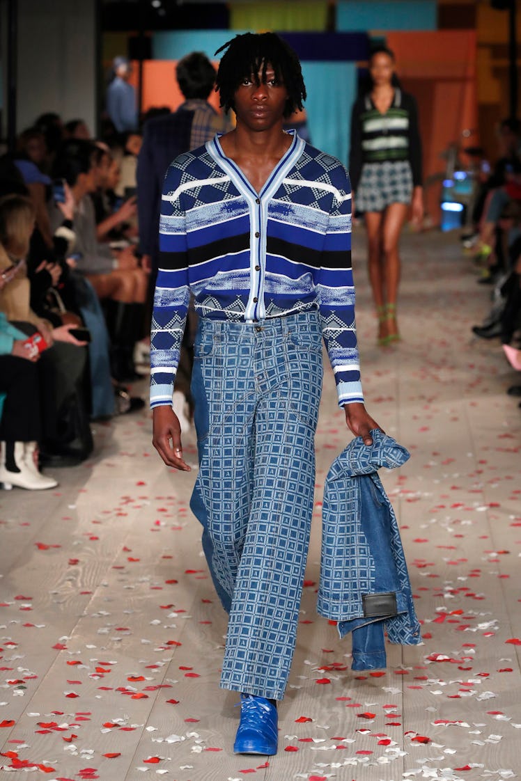 A model in a blue-white cardigan and blue denim jeans with geometric print by Ahluwalia 