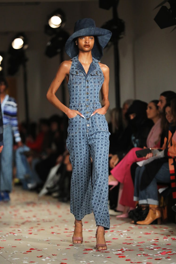 A model in a blue denim jumpsuit with geometric print and hat by Ahluwalia at the London Fashion Wee...