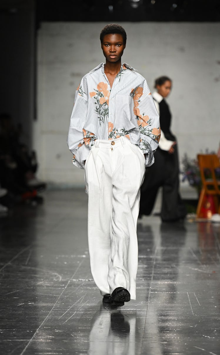 A model in a white floral shirt and white pants by S. S. Daley at the London Fashion Week Fall 2022