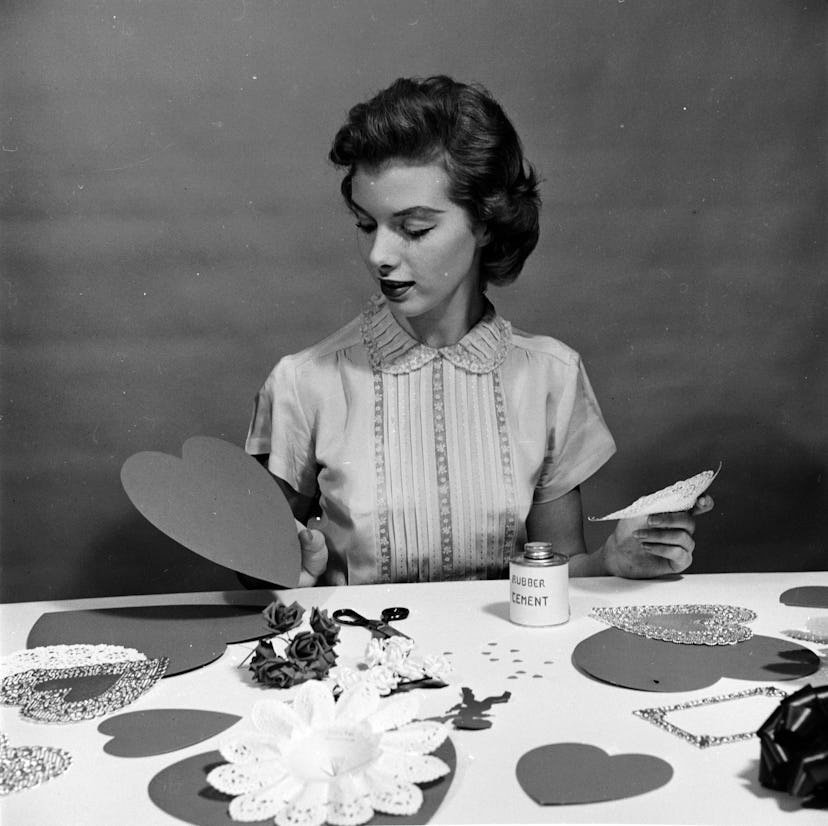 A woman in the 1950s makes homemade valentines cards. Here are Valentine's Day trivia questions and ...