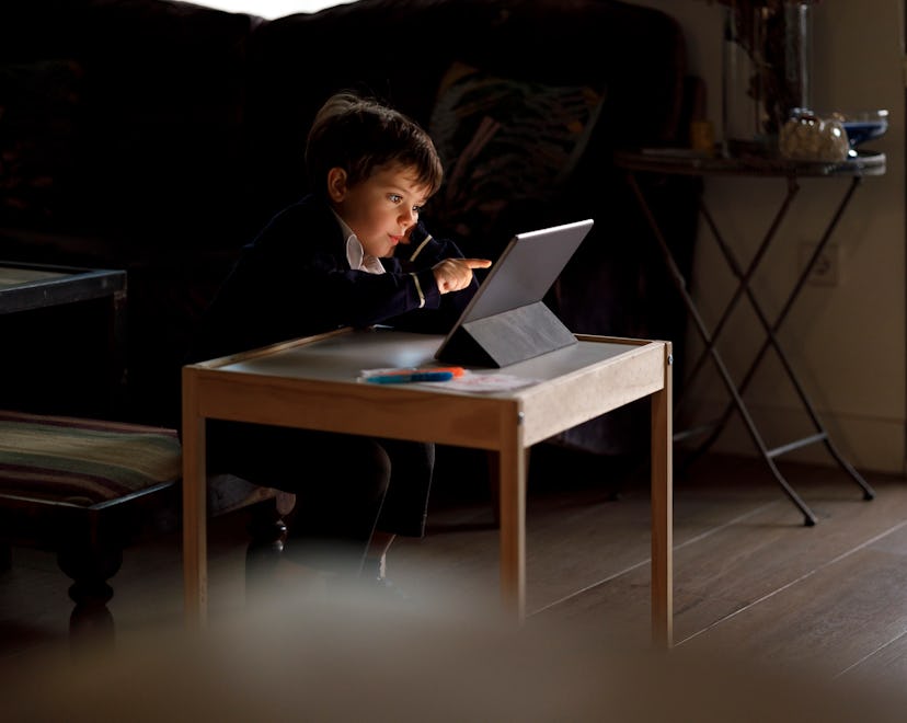 Handsome boy in school uniform teaching online class at home with a tablet.