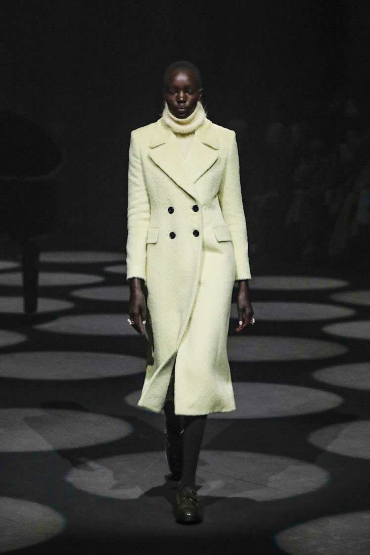 A model walking in a cream coat and turtleneck by Erdem at the London Fashion Week Fall 2022